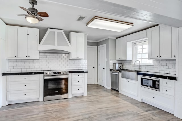 kitchen with white cabinets, custom range hood, and appliances with stainless steel finishes