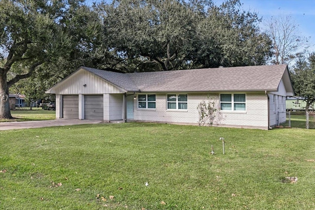 ranch-style house featuring a front lawn, concrete driveway, roof with shingles, and an attached garage