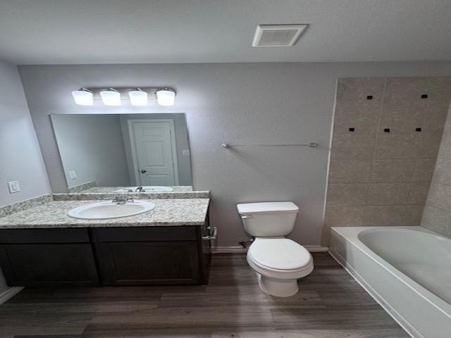 full bathroom with vanity, hardwood / wood-style flooring, toilet, and tiled shower / bath