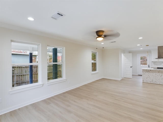 unfurnished living room with ornamental molding, a healthy amount of sunlight, and light wood-type flooring