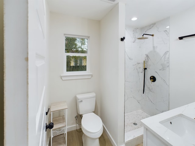 bathroom with hardwood / wood-style flooring, vanity, toilet, and a tile shower