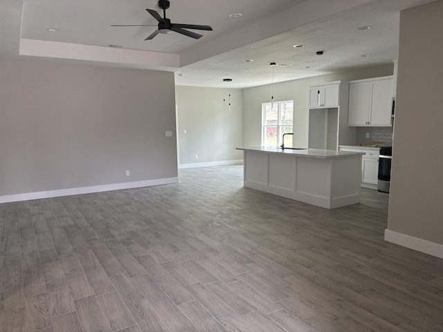 3240 Taft Ave, Groves, TX 77619 - unfurnished living room featuring baseboards, a tray ceiling, wood finished floors, and ceiling fan