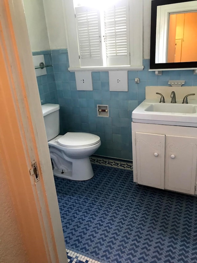 bathroom featuring tile patterned floors, vanity, toilet, and tile walls