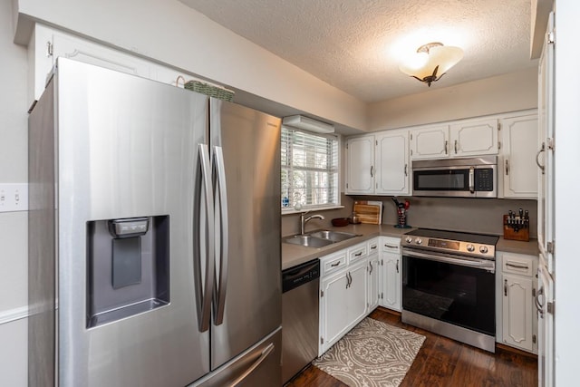 kitchen with dark wood-type flooring, sink, a textured ceiling, appliances with stainless steel finishes, and white cabinets