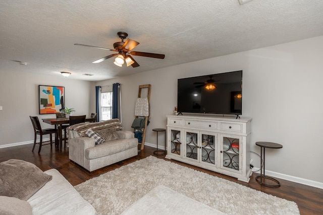 living room with ceiling fan, dark wood-type flooring, and a textured ceiling