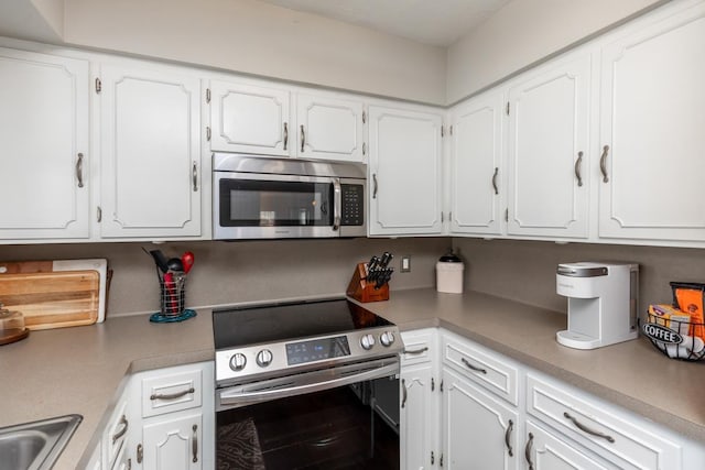 kitchen featuring stainless steel appliances, white cabinetry, and sink