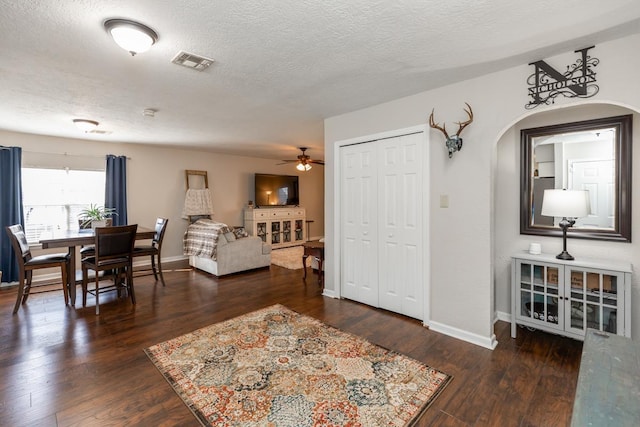 interior space featuring ceiling fan, dark wood-type flooring, and a textured ceiling