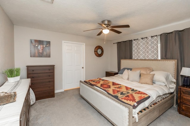 bedroom featuring ceiling fan, light carpet, and a textured ceiling