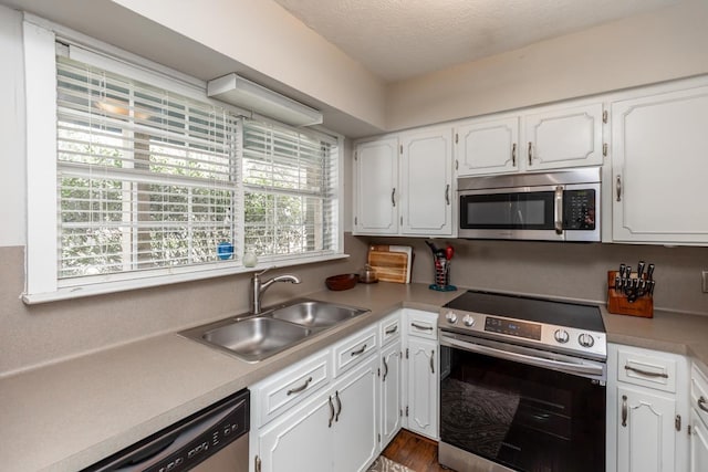 kitchen with white cabinetry, appliances with stainless steel finishes, sink, and a textured ceiling