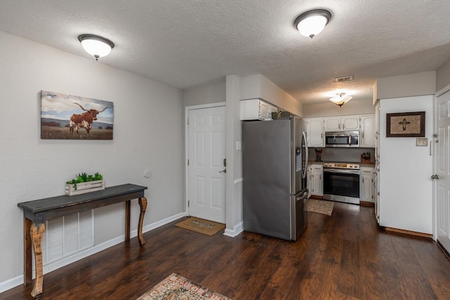 kitchen featuring stainless steel appliances, white cabinetry, dark hardwood / wood-style floors, and a textured ceiling