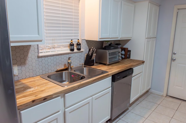 kitchen with stainless steel dishwasher, butcher block counters, white cabinetry, tasteful backsplash, and a sink