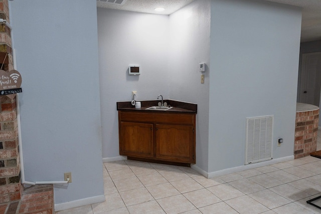 bathroom with a sink, baseboards, tile patterned flooring, and visible vents