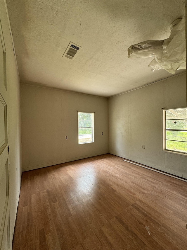 unfurnished room featuring light hardwood / wood-style flooring and a textured ceiling