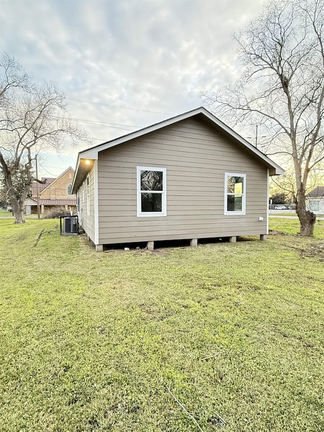 view of side of property with a yard and cooling unit