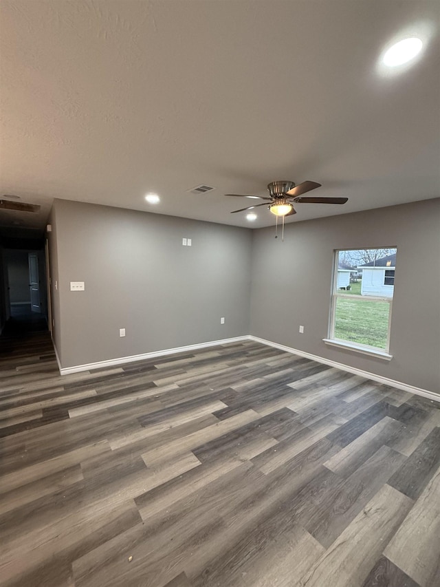 unfurnished room featuring dark wood-type flooring, visible vents, and baseboards