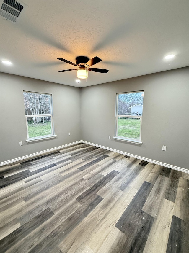 spare room featuring visible vents, baseboards, and wood finished floors