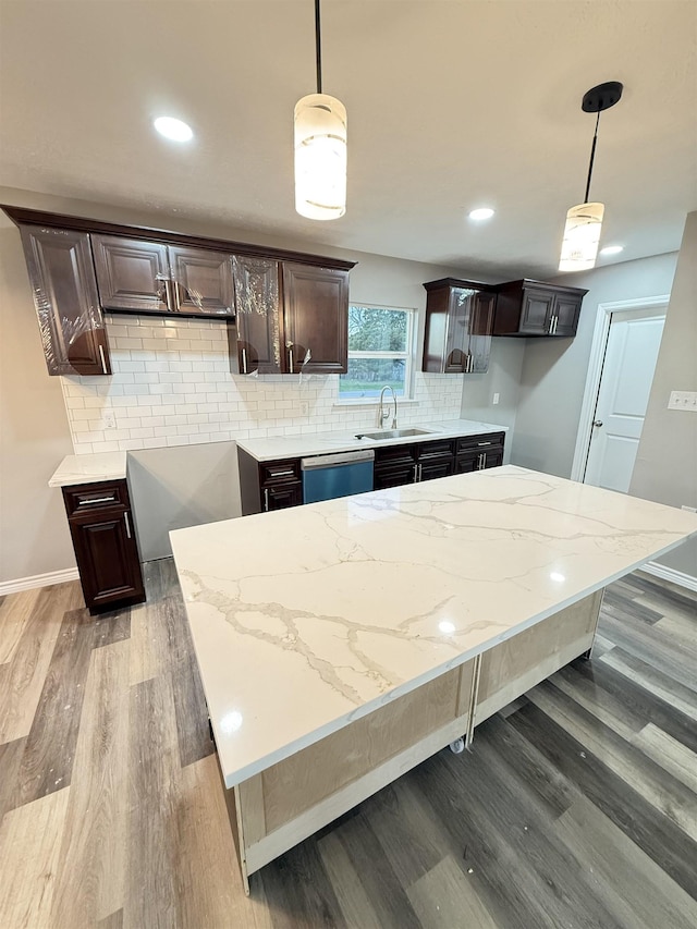 kitchen featuring backsplash, a sink, dark brown cabinets, wood finished floors, and dishwasher