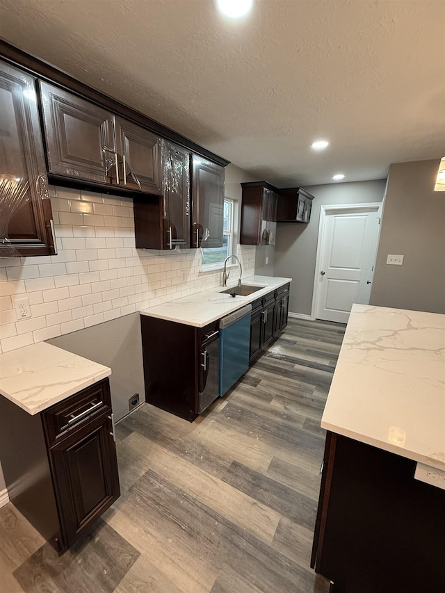 kitchen with dark wood-style flooring, tasteful backsplash, a sink, dark brown cabinets, and dishwashing machine