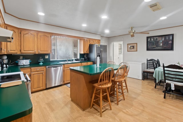 304 Whipoorwill Dr, Silsbee, TX 77656 - kitchen featuring appliances with stainless steel finishes, a sink, a kitchen breakfast bar, light wood finished floors, and ceiling fan
