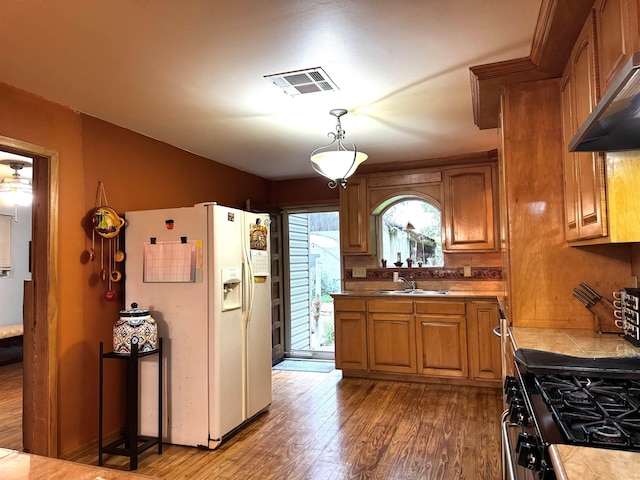 2940 36th St, Port Arthur, TX 77642 - kitchen with white refrigerator with ice dispenser, dark wood-style floors, exhaust hood, brown cabinets, and range with gas cooktop