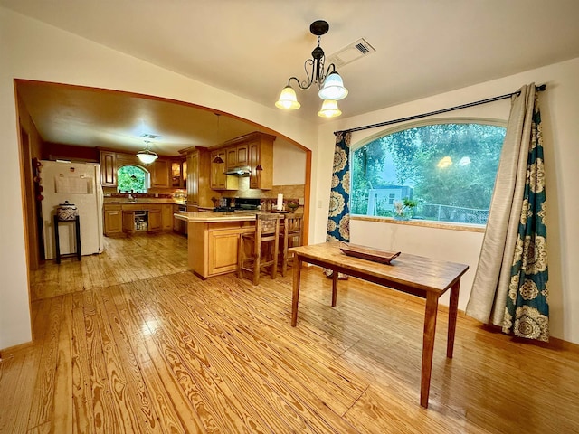 2940 36th St, Port Arthur, TX 77642 - dining room featuring light wood-style floors, a chandelier, and arched walkways