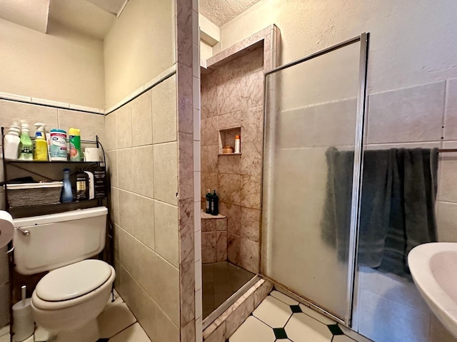 bathroom featuring toilet, a tile shower, and tile walls