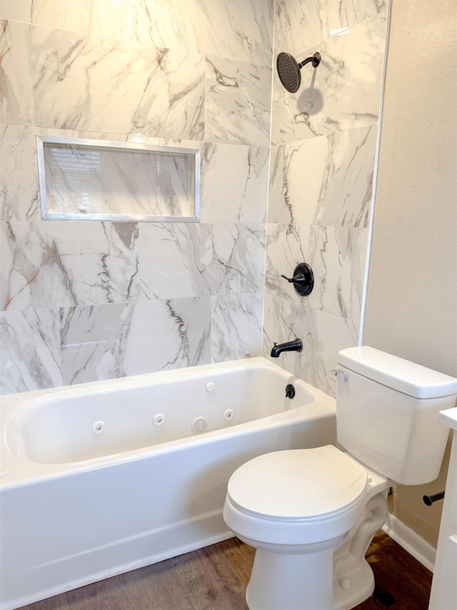 bathroom with toilet, hardwood / wood-style floors, and tiled shower / bath