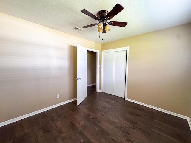 unfurnished bedroom with ceiling fan, dark hardwood / wood-style flooring, and a closet