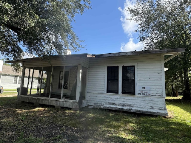 view of property exterior featuring a sunroom and a yard