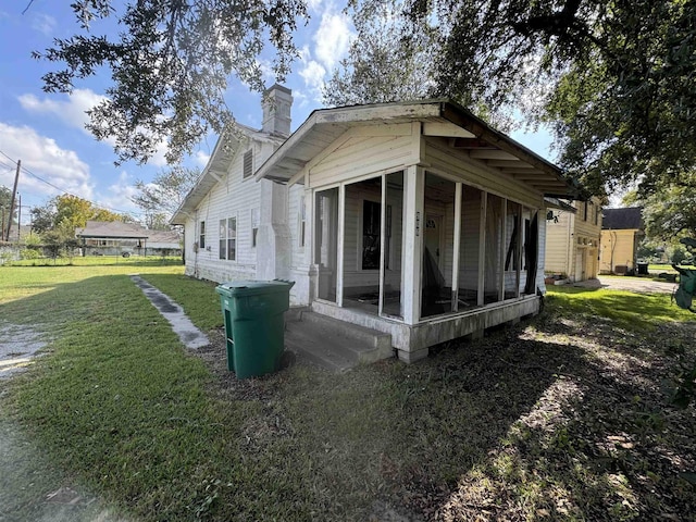 view of home's exterior with a sunroom and a lawn