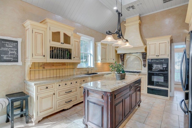 kitchen featuring pendant lighting, a kitchen island, appliances with stainless steel finishes, and cream cabinets