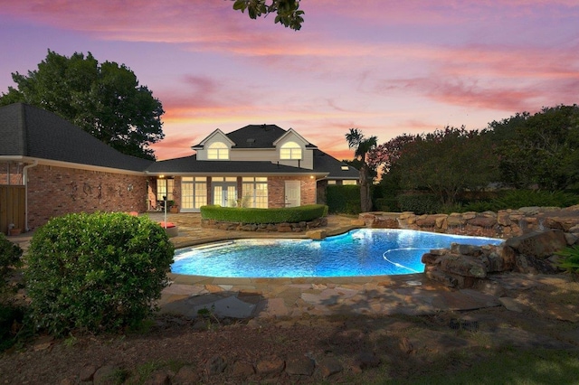 pool at dusk with a patio area