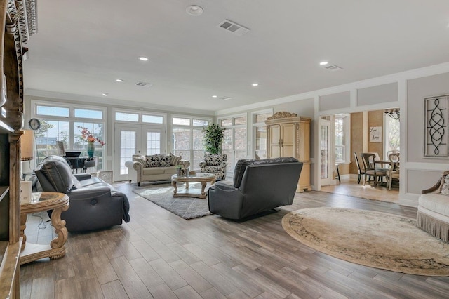 living room featuring light hardwood / wood-style floors, ornamental molding, and french doors