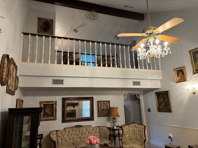 living room featuring beam ceiling, ceiling fan, and a high ceiling