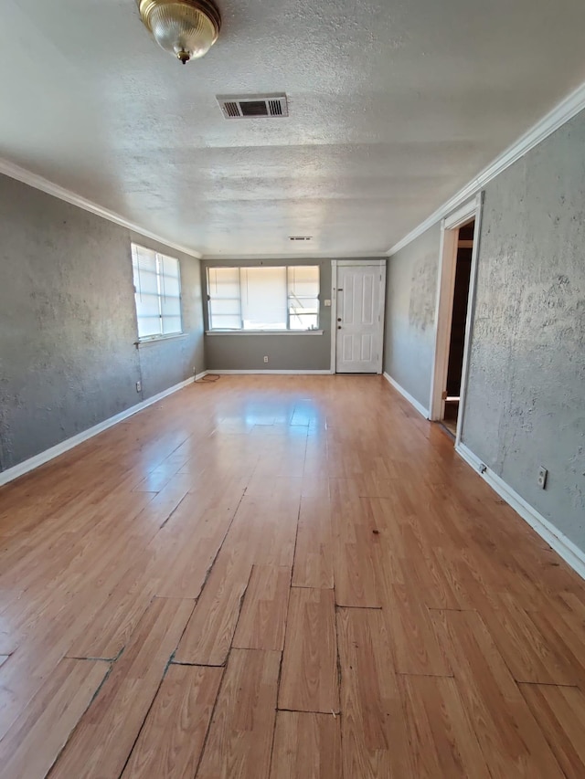 spare room featuring light hardwood / wood-style floors, ornamental molding, and a textured ceiling