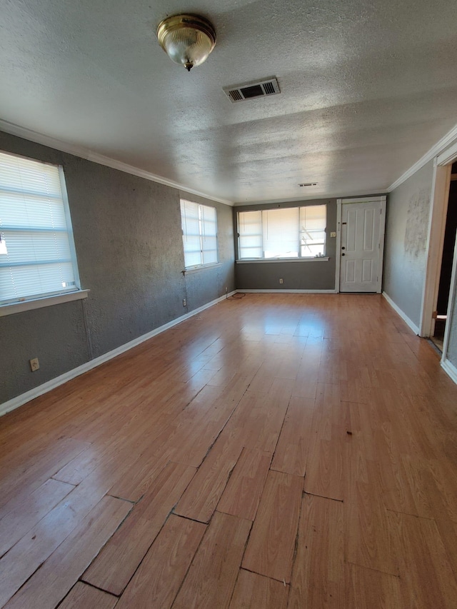 interior space featuring light hardwood / wood-style flooring, a textured ceiling, and ornamental molding