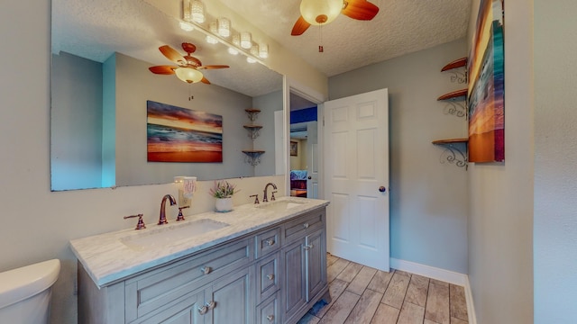 bathroom with vanity, ceiling fan, toilet, and a textured ceiling