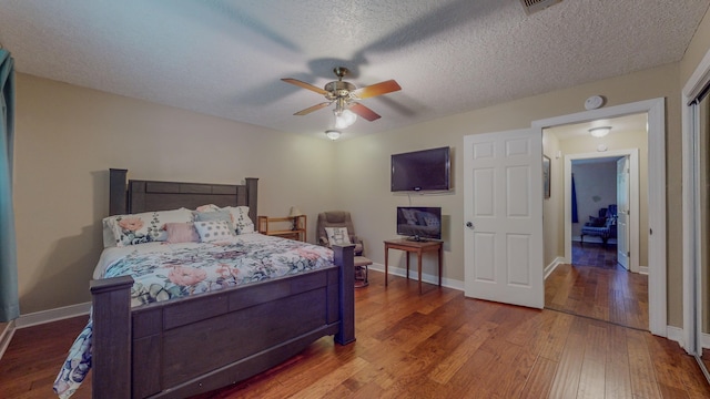 bedroom with ceiling fan, hardwood / wood-style floors, and a textured ceiling