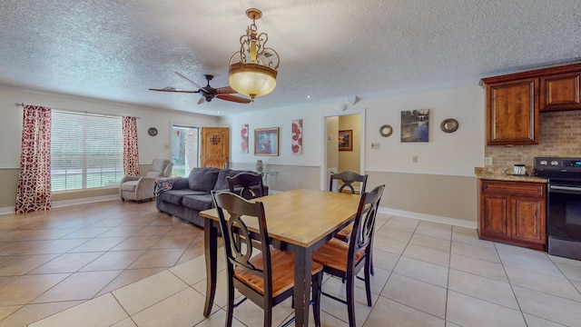 dining area with ceiling fan, light tile patterned floors, and a textured ceiling