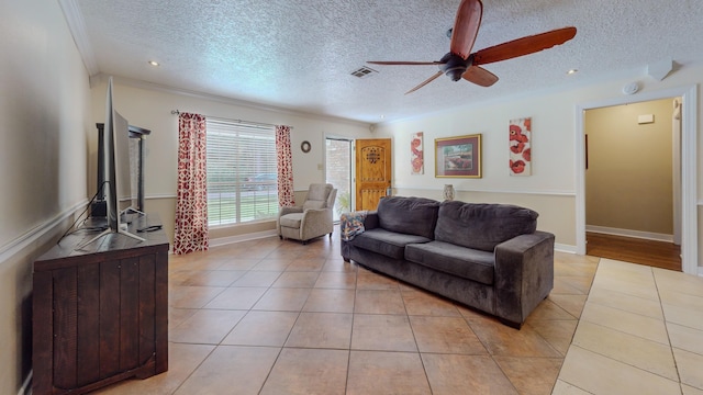 living room with ceiling fan, light tile patterned flooring, and a textured ceiling