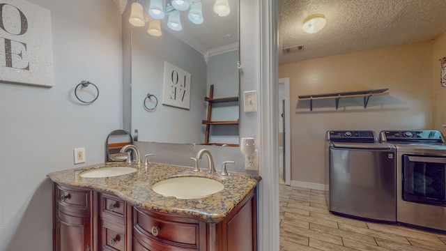 bathroom featuring crown molding, washer and clothes dryer, vanity, and a textured ceiling