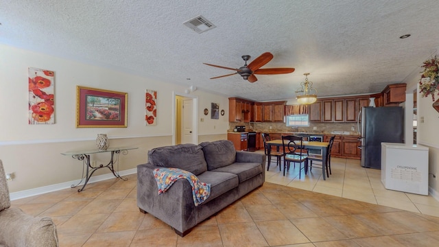 living room with ceiling fan, light tile patterned floors, and a textured ceiling