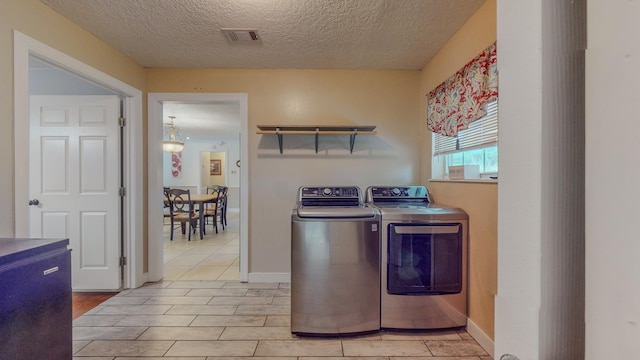 clothes washing area featuring washer and dryer, light tile patterned floors, and a textured ceiling