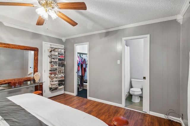 bedroom featuring ensuite bath, ceiling fan, dark wood-type flooring, crown molding, and a textured ceiling