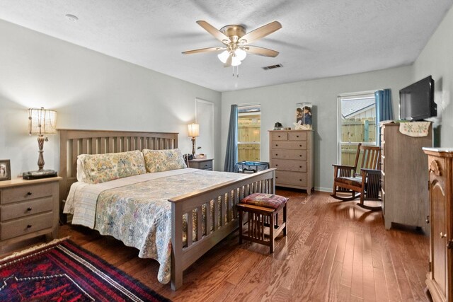 bedroom featuring baseboards, hardwood / wood-style flooring, visible vents, and a ceiling fan