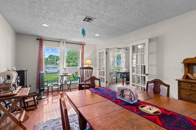 dining space featuring hardwood / wood-style floors, a textured ceiling, french doors, visible vents, and recessed lighting
