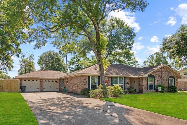 single story home with concrete driveway, fence, brick siding, an attached garage, and a front yard