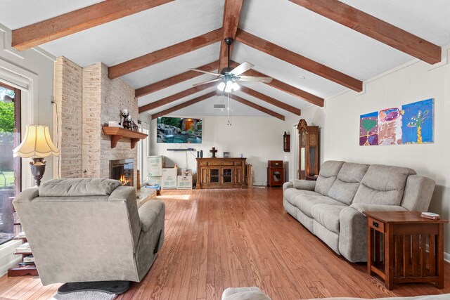 living area featuring vaulted ceiling with beams, wood finished floors, a fireplace, and ceiling fan