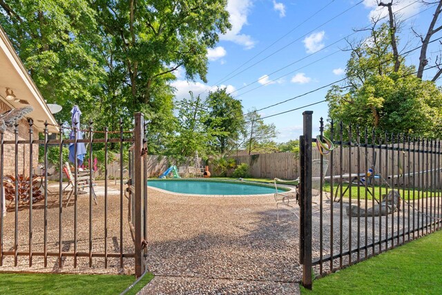 view of pool with fence, a fenced in pool, and a playground