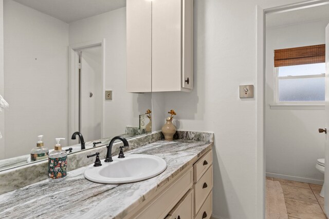 bathroom with tile patterned flooring, baseboards, toilet, and vanity